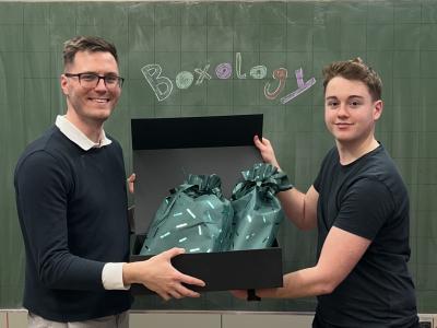 Schüler und Lehrer halten Box in die Kamera
